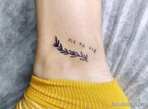 Фото тату с изображением веточки и надписи "Vis ta vie" на запястье. Минималистичный черно-белый рисунок татуировки.