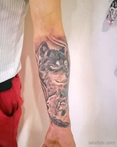 Фото тату волчицы с волчонком на руке. Реалистичный стиль, мягкие тона и трогательный сюжет.
