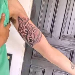 Фото тату двух голов волка, смотрящих в разные стороны, выполненных в черно-серых тонах на предплечье. Изображение детализированное и выразительное.