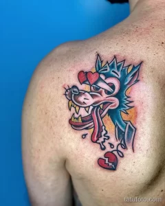 Фото тату волка с разбитым сердцем на плече. Яркий рисунок в стиле traditional tattoo с использованием насыщенных цветов и четких контуров.