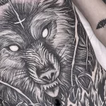 Фото тату волка на боку, выполненное в технике blackwork. Детализированный рисунок с реалистичным изображением головы волка и текстурой шерсти.