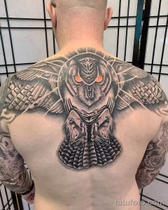 Фотография большой татуировки совы на спине, выполненной в технике blackwork с использованием геометрических узоров и точечной штриховки.