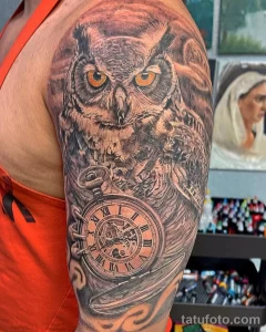 Черно-серая татуировка совы и карманных часов на руке. Реалистичное изображение птицы и старинных часов с римскими цифрами.