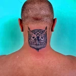 Фото тату совы на затылке, выполненное в черном цвете. Простой, но выразительный рисунок с геометрическими элементами.