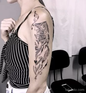 Фото татуировки в стиле blackwork с изображением абстрактного узора, пера и сердца на плече.