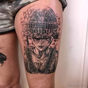Черно-белая татуировка на бедре с изображением солдата в каске, курящего сигарету, окруженного символами войны.