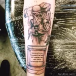 Фото тату на руке с изображением солдата в окопе и надписью "Here Rests in Honored Glory an American Soldier". Татуировка выполнена в черно-серых тонах и символизирует память и уважение.