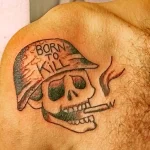 Фото тату на груди: череп в военной каске с надписью "Born to Kill". Черно-белая графика, агрессивный стиль.