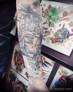Фото тату на руке: старинный самолет, облака, японский стиль. Черно-серый рисунок с детальной проработкой. Эскиз тату для любителей авиации и восточной культуры.