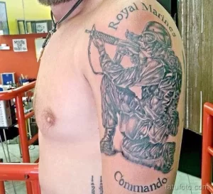 Фото тату на плече: морской пехотинец с оружием и надписью "Royal Marines Commando". Черно-серый рисунок татуировки в реалистичном стиле.