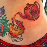 Фото тату на боку: красочный рисунок с чайником, коктейлем, надписью "Drink Me" и элементами из "Алисы в Стране чудес". Эскиз татуировки.