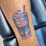 Фото тату на предплечье: яркий рисунок коктейля Havana Club в стакане со льдом. Татуировка в реалистичном стиле с яркими цветами.