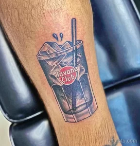 Фото тату на предплечье: яркий рисунок коктейля Havana Club в стакане со льдом. Татуировка в реалистичном стиле с яркими цветами.
