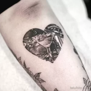 Фото татуировки в стиле blackwork с изображением бокала в форме сердца на руке.
