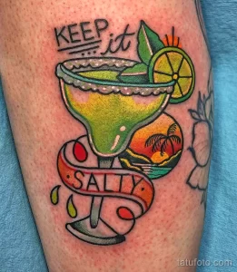 Яркая татуировка маргариты в бокале, украшенная пальмами и надписью "Keep it Salty". Стиль олд скул.