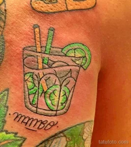 Фотография татуировки коктейля 'мамбо' с дольками лайма и соломинками, выполненной в минималистичном стиле с использованием зеленых оттенков.