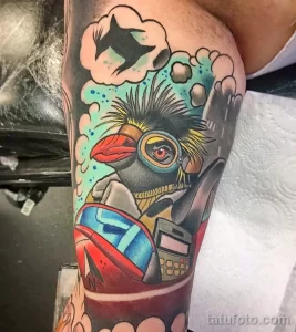 Фото тату пингвина в стиле стимпанк на руке. Рисунок татуировки выполнен в ярких цветах с использованием множества деталей и механизмов.