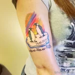 Фото тату двух пингвинов на льдине с датой '19.05.2014' и надписью 'Love Never Fails'. Яркий и красочный рисунок в акварельном стиле.