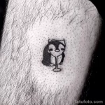 Фото маленькой черно-белой татуировки пингвина в стиле doodle на руке. Простой и милый рисунок татуировки для любителей минимализма.
