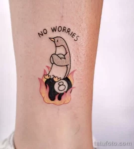 Фото тату пингвина с надписью "No Worries" и бильярдным шаром 8. Яркий дизайн, позитивный посыл, оригинальный рисунок.