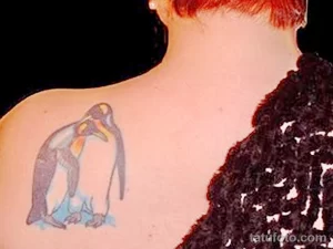 Фото простого эскиза татуировки пингвина на плече, выполненного в черно-белых тонах с добавлением голубых акцентов.