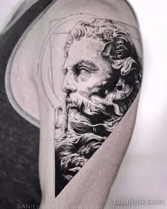 Фото тату: черно-белый портрет Посейдона на плече, выполненный в реалистичном стиле с акцентом на детализацию лица и бороды.