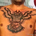 Фото тату совы на груди в стиле blackwork. Изображение включает луну, глобус и сложные узоры, выполненные черными чернилами.