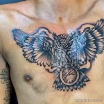 Фото татуировки совы с карманными часами на груди, выполненной в стиле blackwork. Изображение состоит из плотных черных заливок и точечной штриховки.