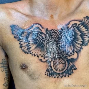 Фото татуировки совы с карманными часами на груди, выполненной в стиле blackwork. Изображение состоит из плотных черных заливок и точечной штриховки.