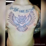 Фото контурной татуировки совы с надписью "Live Life With No Regrets" на груди мужчины. Изображение выполнено в минималистичном стиле.