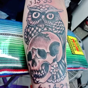 Фото татуировки совы и черепа в стиле blackwork, выполненной полностью черным цветом с использованием геометрических узоров и плотной штриховки.