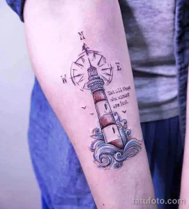 Фото тату маяка с компасом и надписью на предплечье. Черно-белая татуировка с детальной проработкой и морской тематикой.