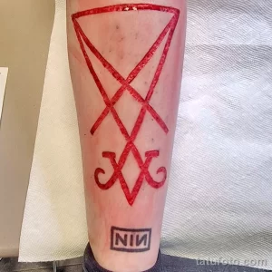 Фото тату на ноге: красный символ Левиафана и логотип группы Nine Inch Nails. Мистический и музыкальный рисунок татуировки.