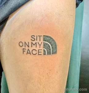 Черно-белая татуировка на предплечье с надписью 'Sit on My Face' и логотипом The North Face.