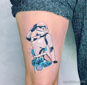 Фото тату на ноге: изображение штурмовика из Star Wars в динамичной позе с надписью 'Fight Win', выполненное в ярких цветах и с брызгами краски.