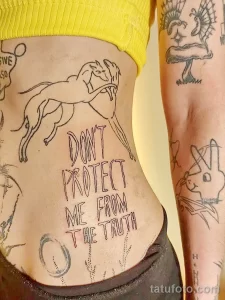 Фото тату: рисунок скачущего коня и надпись "DON'T PROTECT ME FROM THE TRUTH" на животе. Стиль - традиционный, черно-белый рисунок.