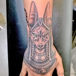 Фото тату Анубиса на предплечье, выполненное в технике blackwork. Детализированный рисунок головы бога с характерными ушами и ошейником.