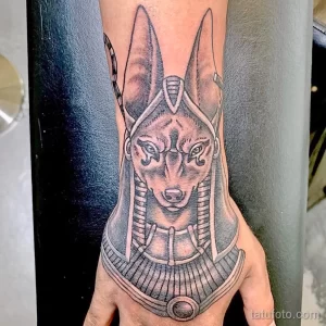 Фото тату Анубиса на предплечье, выполненное в технике blackwork. Детализированный рисунок головы бога с характерными ушами и ошейником.