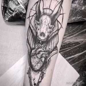 Фото тату Анубиса на ноге в стиле Blackwork. Изображение выполнено в черно-белых тонах с использованием плотных штрихов и геометрических фигур.