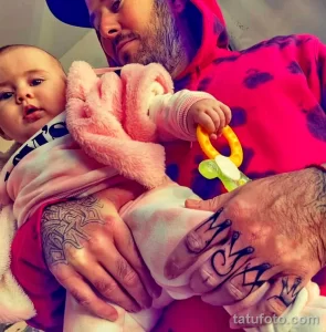 Фото татуировки с надписью 'MAMA' на руке мужчины. Черные чернила, каллиграфический шрифт, минималистичный дизайн.