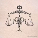 Черно-белое тату Весы с детально прорисованными чашами весов и декоративными элементами. Классический дизайн, подходящий для любителей традиционных татуировок.