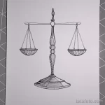 Черно-белое тату с изображением классических весов правосудия. Детализированная прорисовка и использование штриховки создают эффект объема и реалистичности.