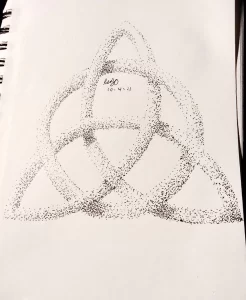 Черно-белое фото тату, выполненного в технике pointillism. Изображение состоит из множества точек, образующих треугольную форму.