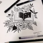 Черно-белый эскиз татуировки с открытой книгой, украшенной цветами и полумесяцем. Идеально для любителей литературы и мистики.
