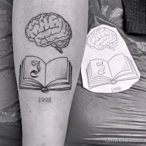 Фото тату на предплечье: изображение мозга и открытой книги, выполненное в технике дотворк. Минималистичный дизайн и символическое значение.