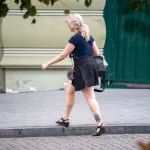 Фотография татуировки на лодыжке девушки, небольшой рисунок, вероятно, цветочный или геометрический узор. Уличная фотография.