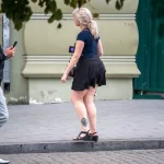 Фотография татуировки на лодыжке девушки, небольшой рисунок, вероятно, цветочный или геометрический узор. Уличная фотография.