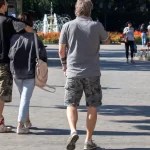 Фотография мужчины с татуировкой на руке, идущего с женщиной по улице. Татуировка в стиле орнамент, на предплечье.