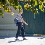 Фото тату: Черный ворон с красными брызгами на плече девушки. Детализированный рисунок татуировки в стиле стрит-арт.