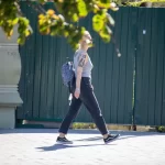 Фотография уличной моды в Одессе: женщина с татуировкой на руке идет по улице, неся рюкзак.